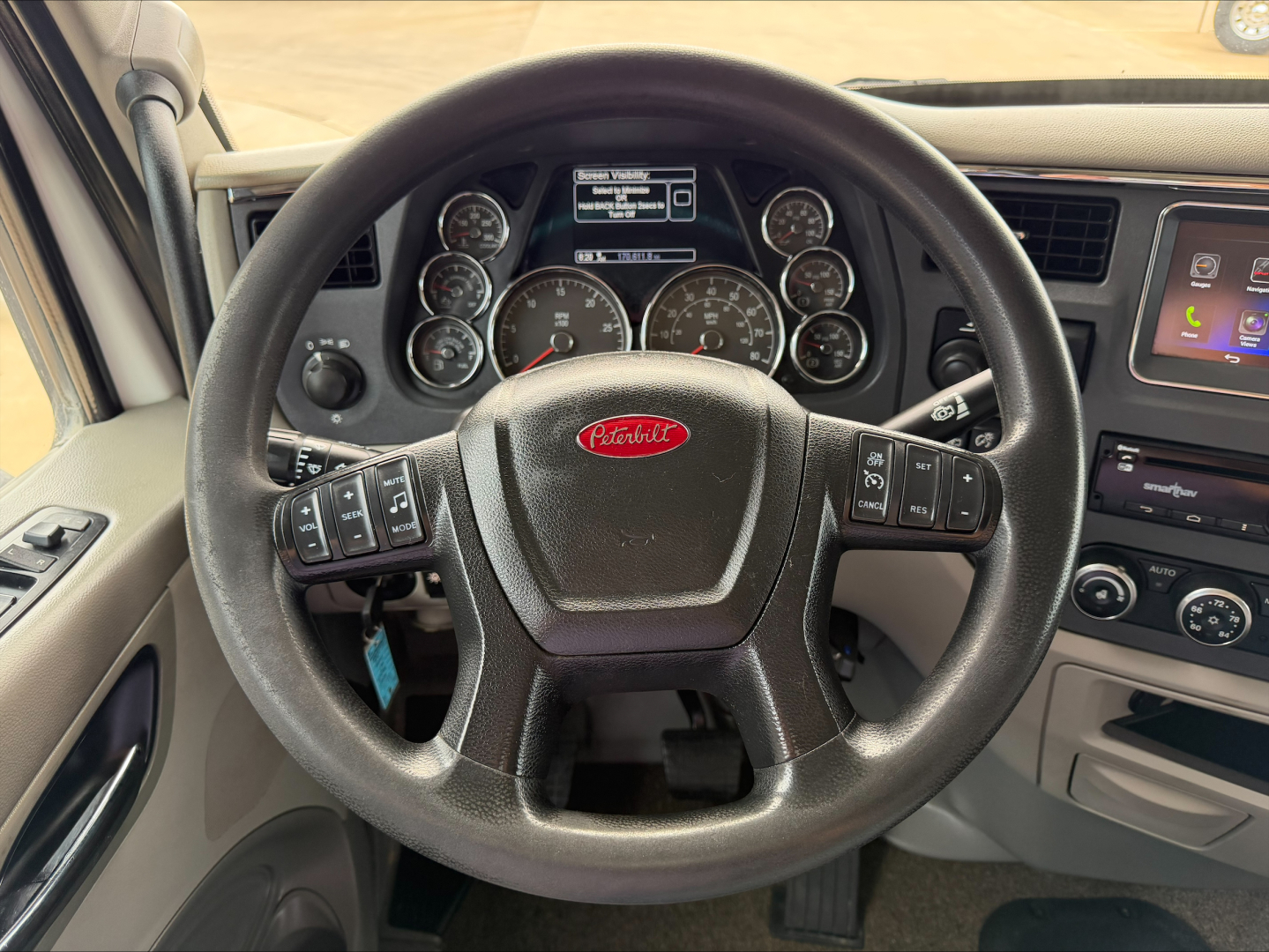 Peterbilt steering wheel in-cab view with gauges and digital display; dashboard text visible including Peterbilt logo on steering wheel