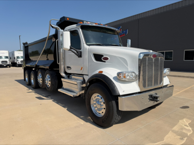 Peterbilt 567 dump truck in service showing chrome front grille, white cab, dual rear axles, and dump bed.