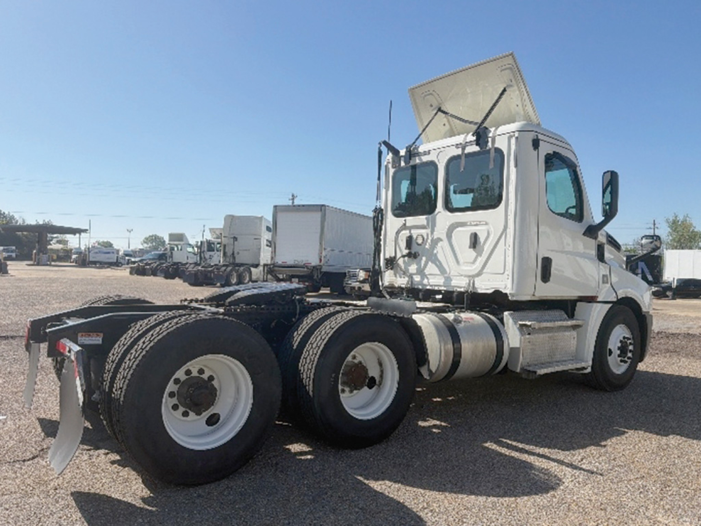Truck chassis and cab of a Freightliner Cascadia126 daycab, rear duals visible, exhaust, fuel tanks, and cab interior windshield area visible.