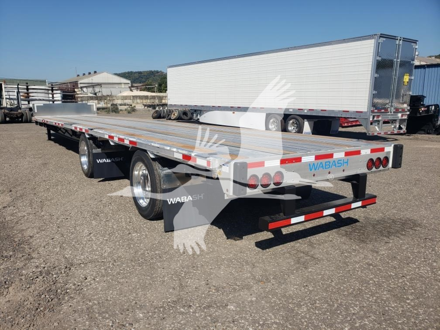 Trailer rear/side view of a Wabash Combo Low Pro 17.5 trailer showing tandem axles, metal decking, reflective tape, and Wabash branding.
