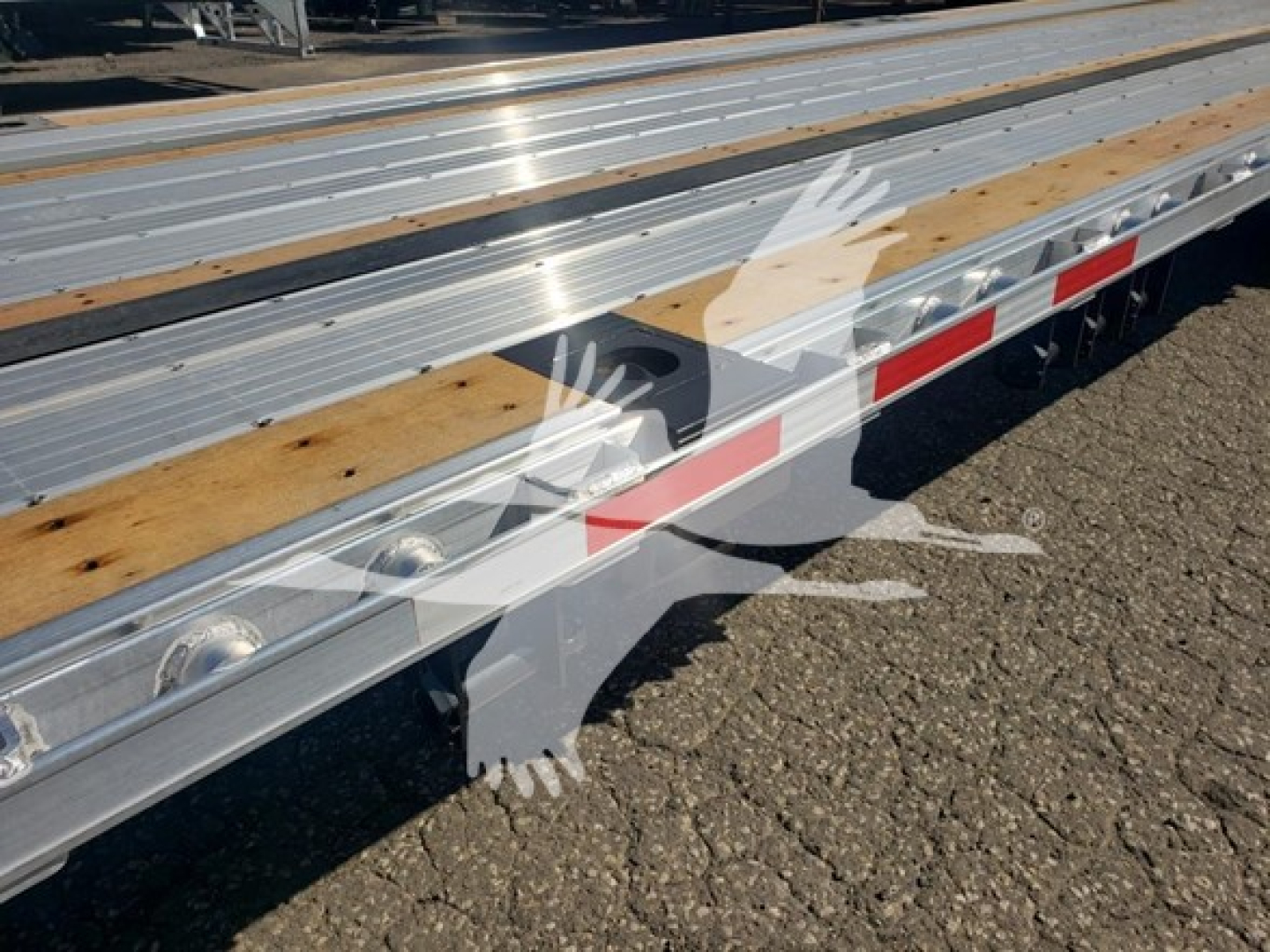 Trailer deck with silver metal beams and wooden planks; side rail with reflective red and white tape; watermark overlay of a handprint graphic.