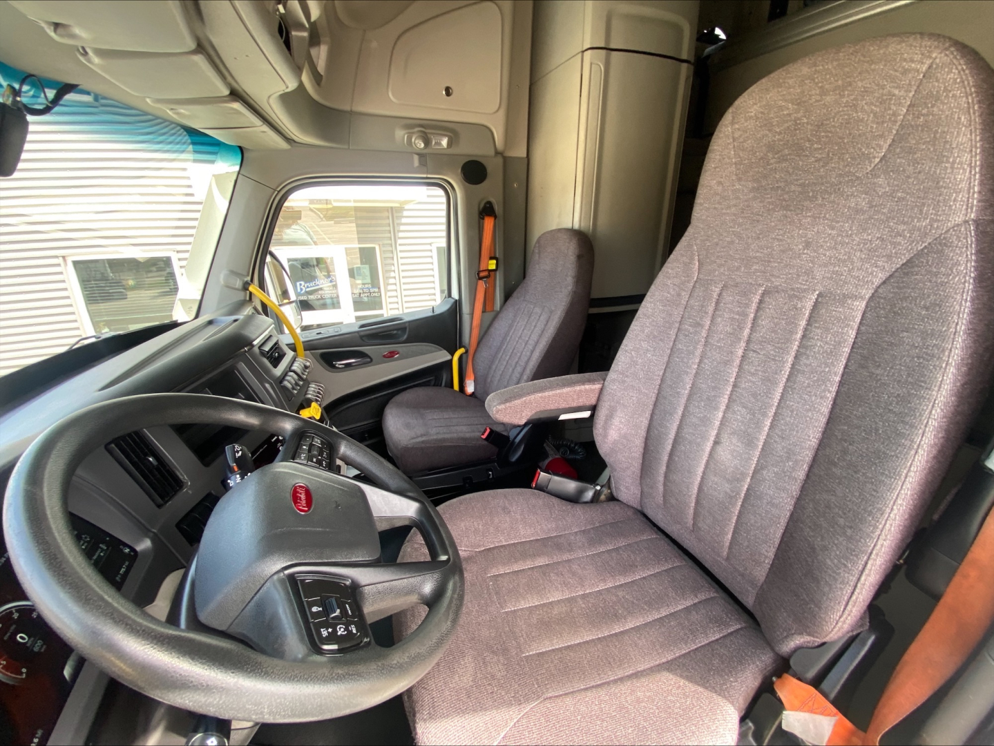 Semi truck cab interior showing steering wheel, driver's seat, and dashboard from a Peterbilt 579.