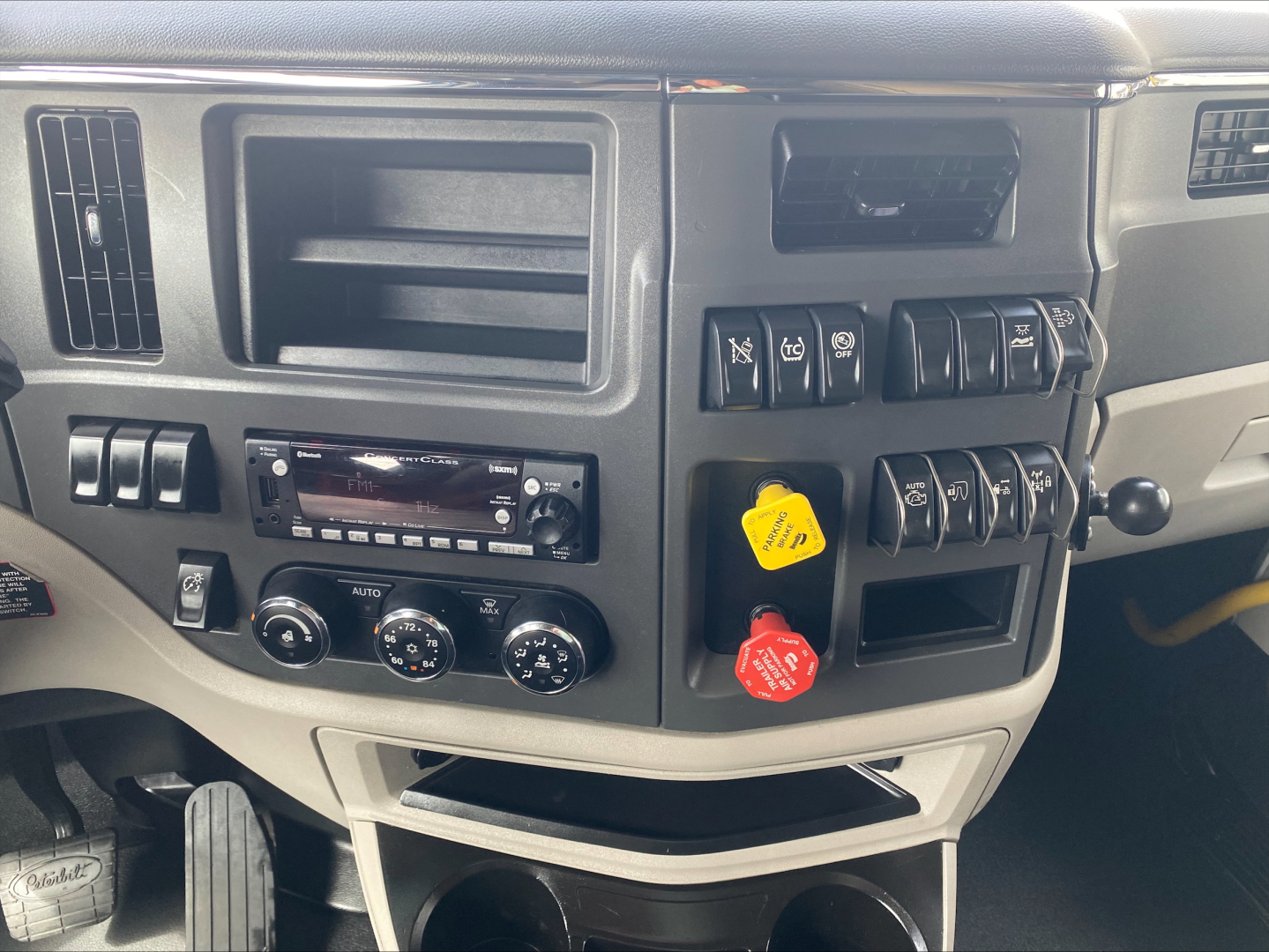 Dashboard and center console of a 2022 Peterbilt 579 with climate controls, radio, and multiple switch panels visible.
