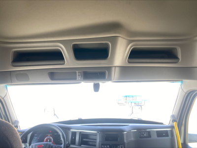 Peterbilt 579 dash area with steering wheel and instrument cluster; front windshield and overhead console visible.