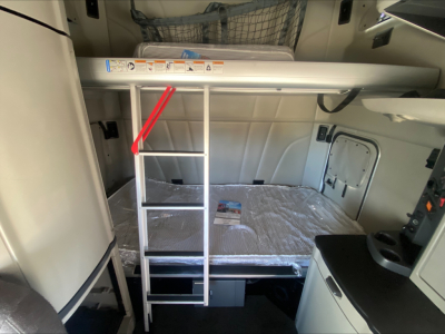 Peterbilt 579 sleeper cab interior with upper bunk and ladder, compact ladder with red handhold leading to bunk area.