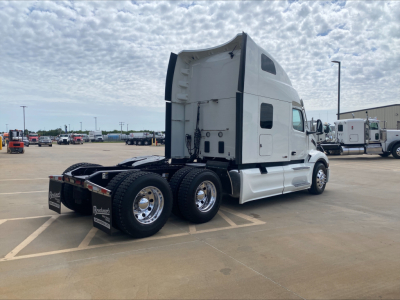Peterbilt 579 tractor cab in an empty lot, side view showing sleeper cab and rear dual axles.