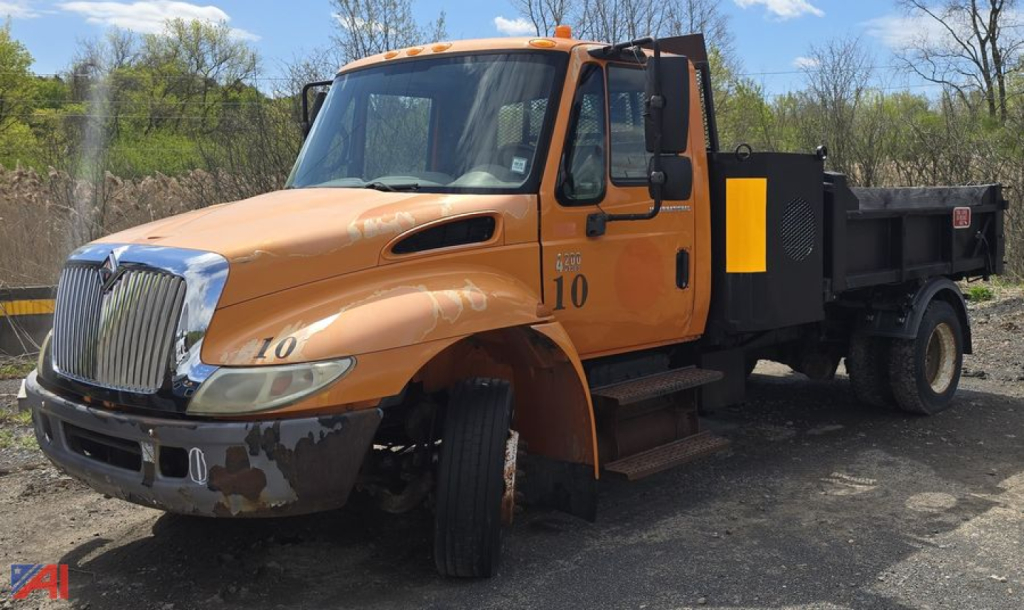 Dump truck cab and dump bed showing International VT365 engine, orange paint, number 10 on door, steel steps, and black dump bed
