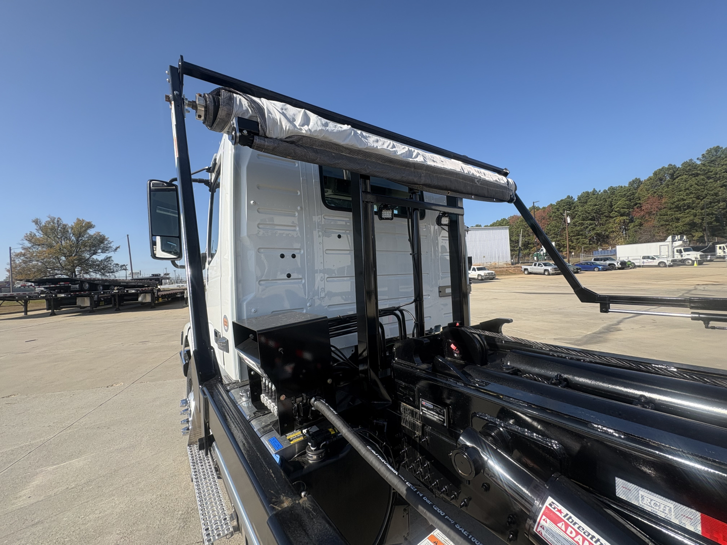 Volvo VHD64B300 chassis cab view showing side frame and hydraulic components under a white cab in a truck yard.
