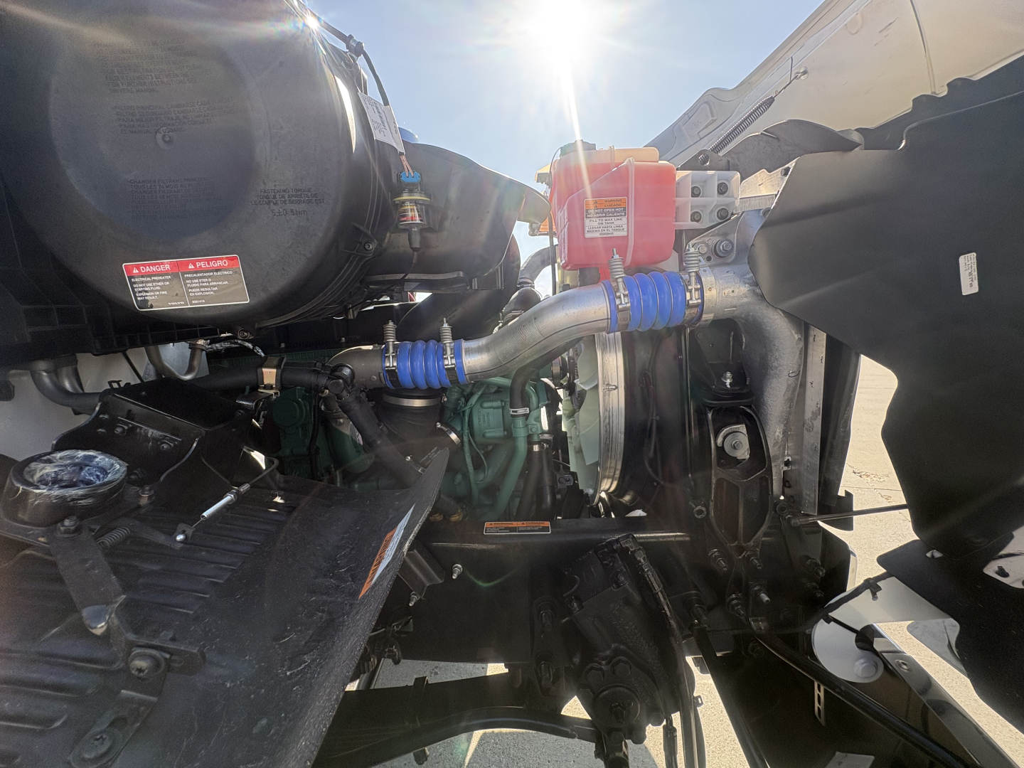 Volvo VHD64B300 truck engine bay showing coolant reservoir, belts, hoses, and engine components.