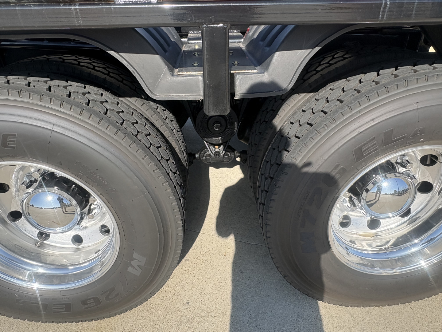 Dual rear wheels and center suspension view of a Volvo VHD64B300 chassis showing twin tires with chrome hubs and linkage between axles.