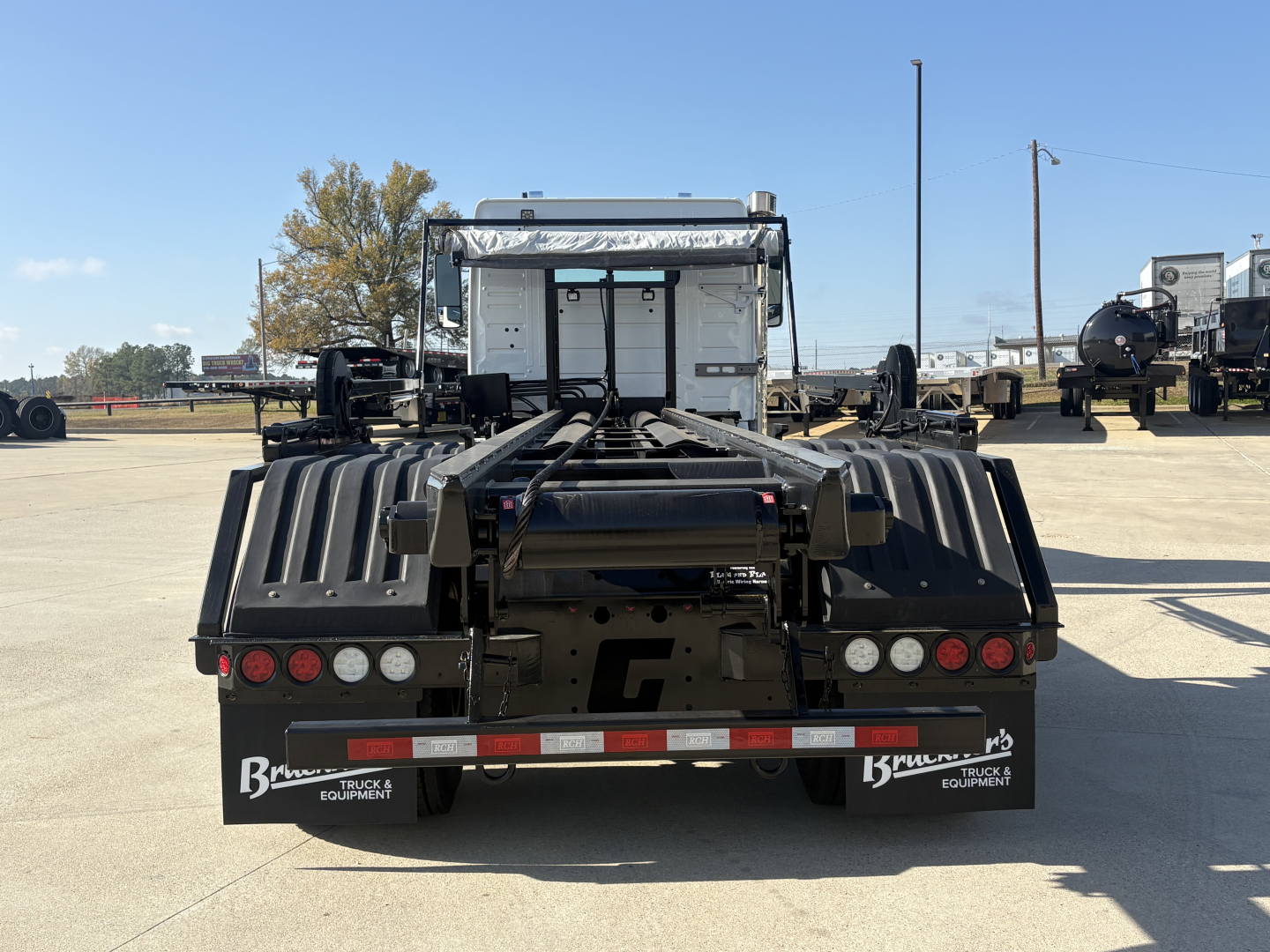 Rear view of 2026 Volvo VHD64B300 rolloff truck showing tail lights, bumper, and chassis with fifth-wheel connection and wheel wells.