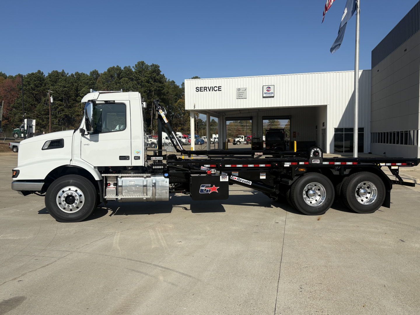 Volvo VHD64B300 roll-off truck side view showing cab, chassis, and dual rear axles with hydraulic machinery.