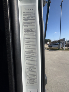 Volvo truck door label showing technical specification stickers with fields like VIN, engine, transmission, axles, paint, and service labels.