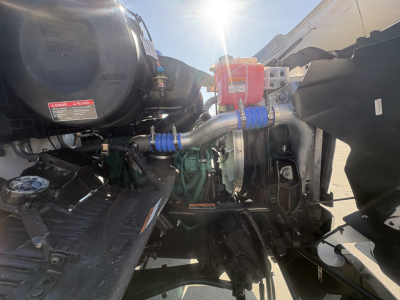 Volvo VHD64B300 truck engine bay showing coolant reservoir, belts, hoses, and engine components.