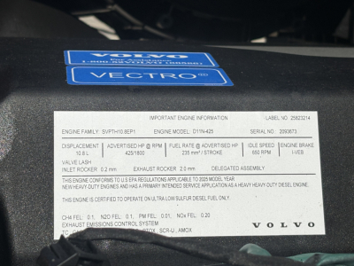 Volvo engine bay showing engine spec label with VIN and engine information plate and blue Volvo/VECTRO stickers.