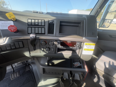 Interior of a Volvo VHD64B300 truck cab showing dashboard with controls, ignition area, red digital display, cup holder, and storage compartments.