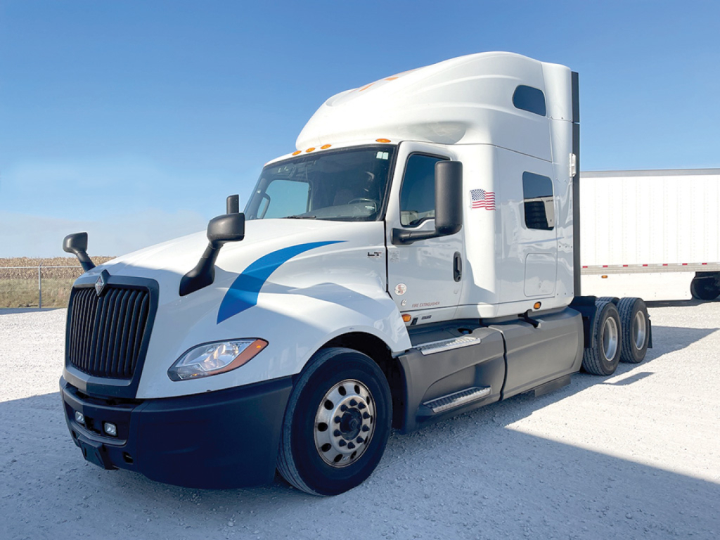 Truck cab exterior of a 2021 International LT625 tractor in a light color with blue graphic, black front bumper, side mirrors, and sleeper cab; no visible text or labels.
