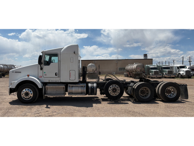 Kenworth T-800 AeroCab tractor showing side profile with chrome fuel tanks and five rear axles under a blue sky.