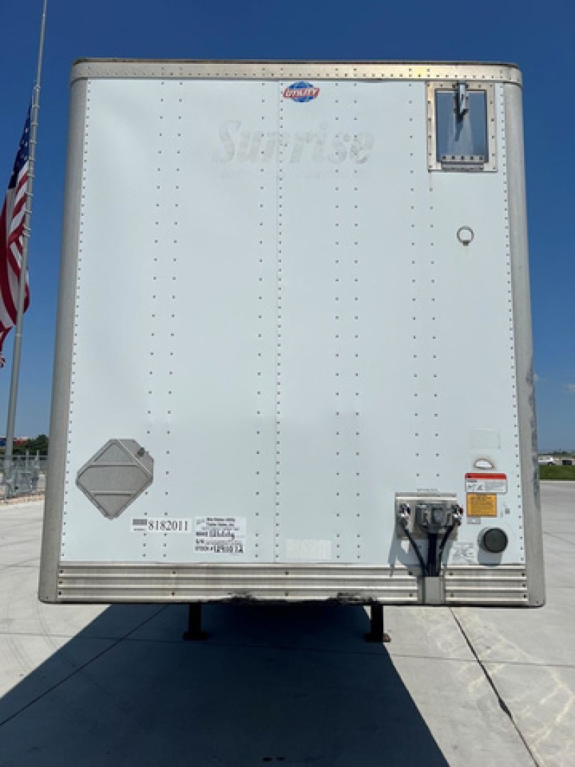 Rear view of a 2014 utility van trailer showing a metallic back door with hinges, a small vent, and registration/sticker labels.