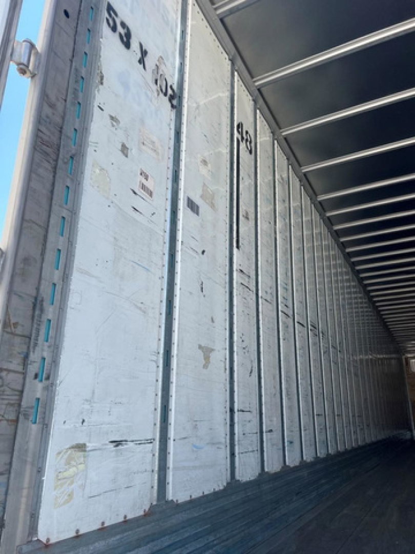 Van trailer interior showing aluminum side walls with numbered markings and ribbed ceiling structure.