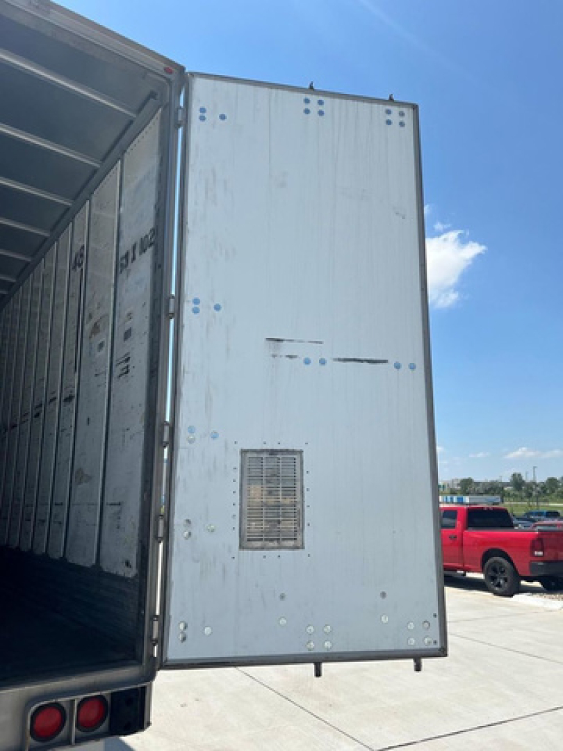 Truck trailer side door open showing interior of a used utility van trailer with light gray exterior, rear vents, and a vented panel on the door.