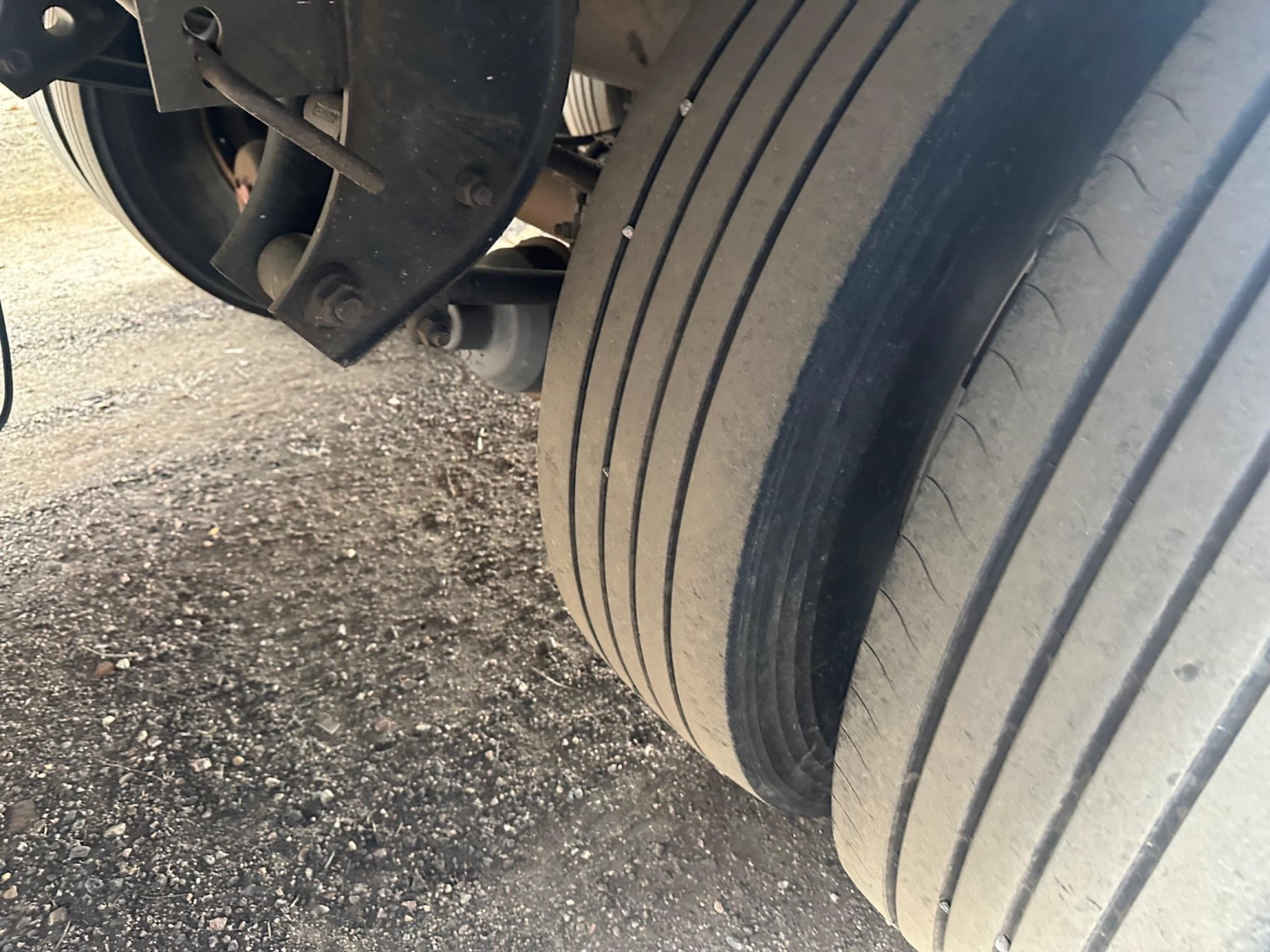 Trailer axle and dual tires with wheel hub and brackets visible in a close-up view under a Great Dane refrigerated trailer.