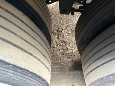 Dual rear trailer tires with tread grooves visible; ground between wheels; part of trailer frame seen at top.