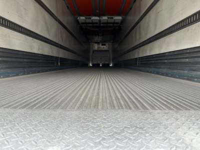 Trailer interior showing empty reefer cargo area with ribbed metal floor and sidewalls, rear doors, and ceiling insulation.