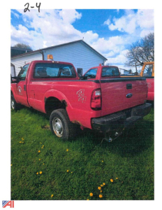 Ford F-350 Super Duty pickup with a V-plow, red extended cab, two-tone, rear view in a grassy yard.