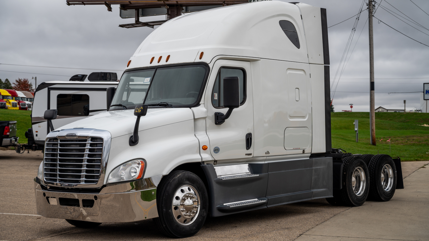 Freightliner Cascadia 125 semi-truck cab in white, side view showing sleeper cab, dual rear axles, chrome bumper and mirrors.