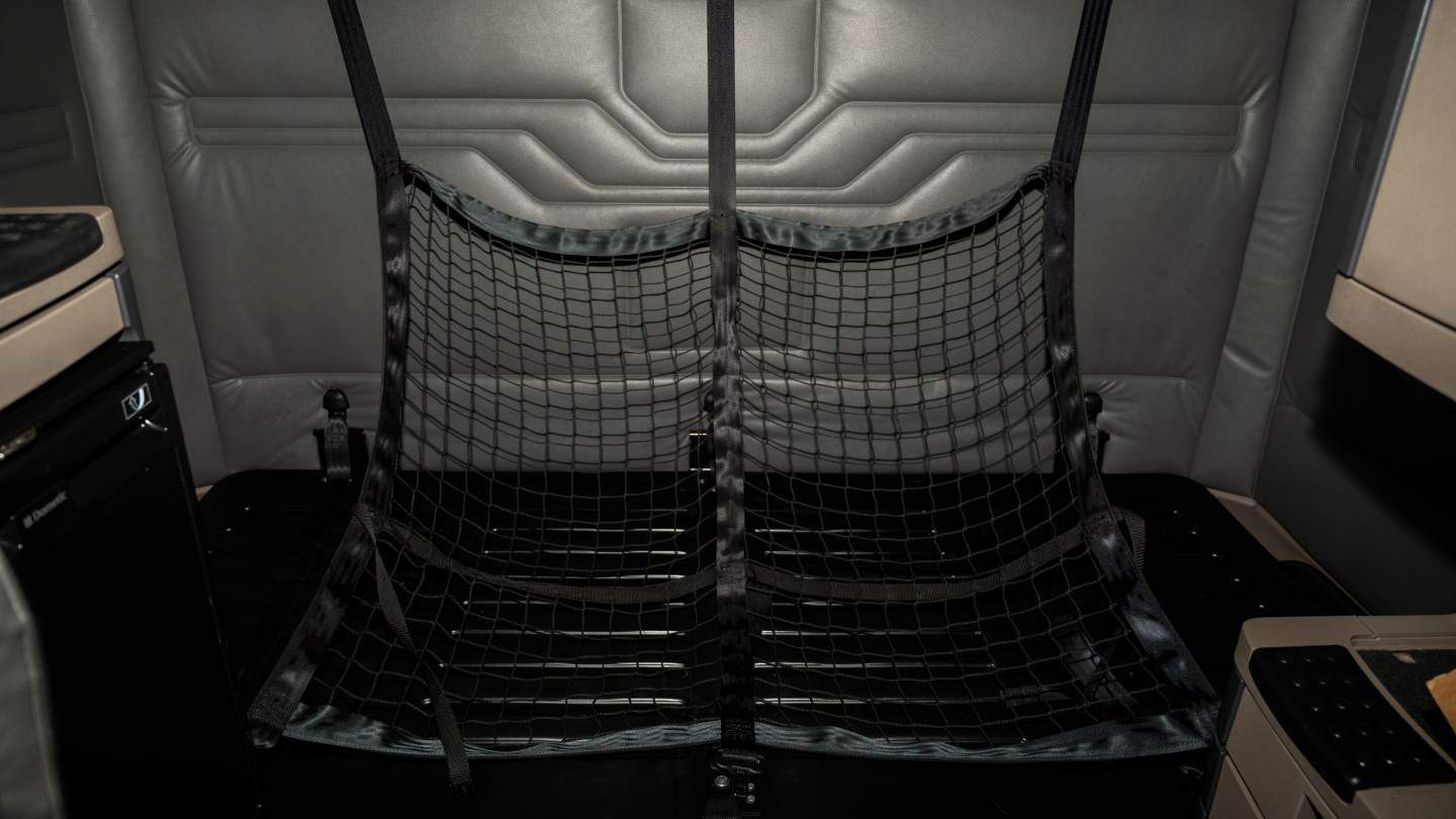 Freightliner Cascadia 125 interior view showing metal driver sleeper area with cargo net barrier and side panels.