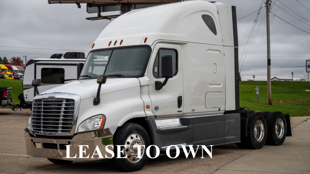 Truck cab and chassis showing Freightliner Cascadia sleeper with white exterior and dual rear axles.