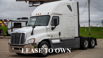 Truck cab and chassis showing Freightliner Cascadia sleeper with white exterior and dual rear axles.