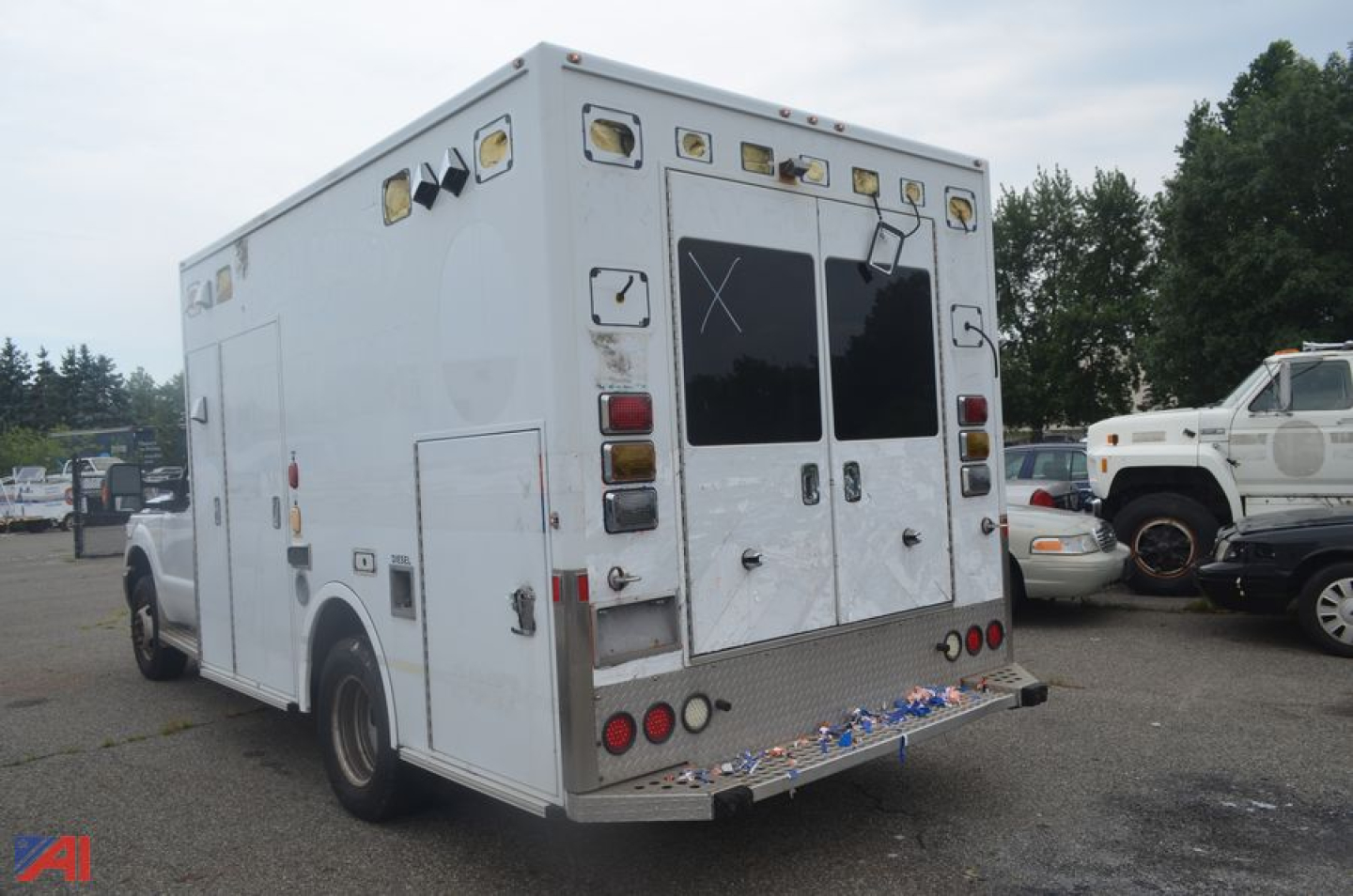 Ambulance rear and side view showing medical emergency vehicle with rear double doors and multiple amber warning lights.