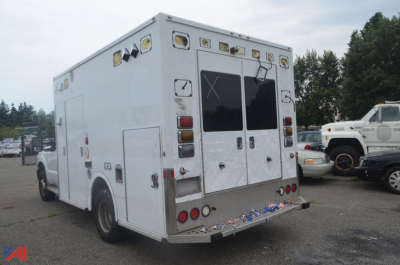 Ambulance rear and side view showing medical emergency vehicle with rear double doors and multiple amber warning lights.