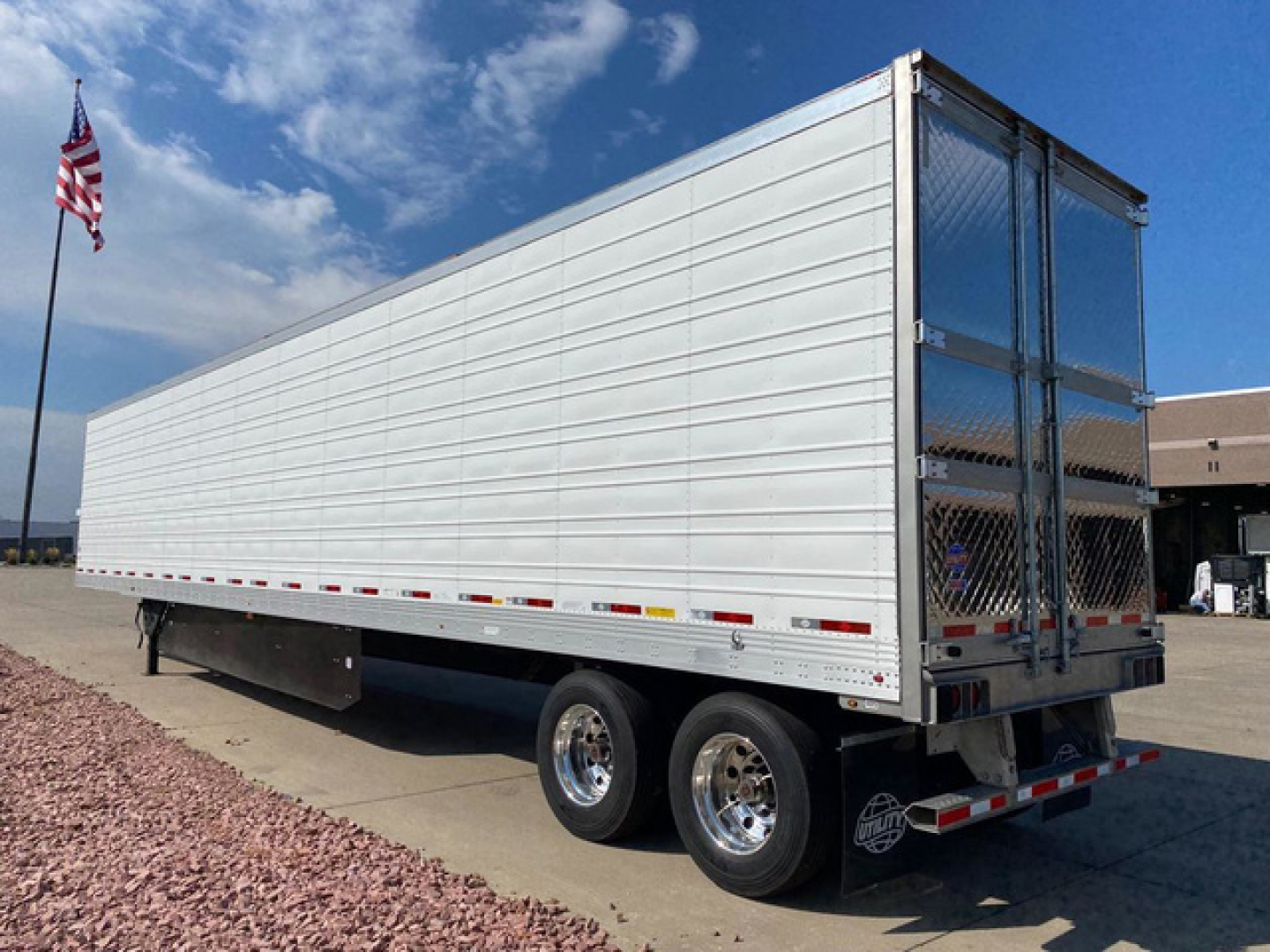 Refrigerated trailer (new) side view showing aluminum panels, tandem axles, and hinged rear doors with diamond plate access.