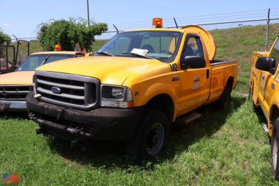 2002 Ford F-250 Super Duty pickup truck angled view in yellow with orange beacon light, front grille, and utility body.