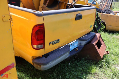 Ford F-250 Super Duty pickup bed rear view showing tailgate and bumper with yellow paint and a brown rear bumper guard.