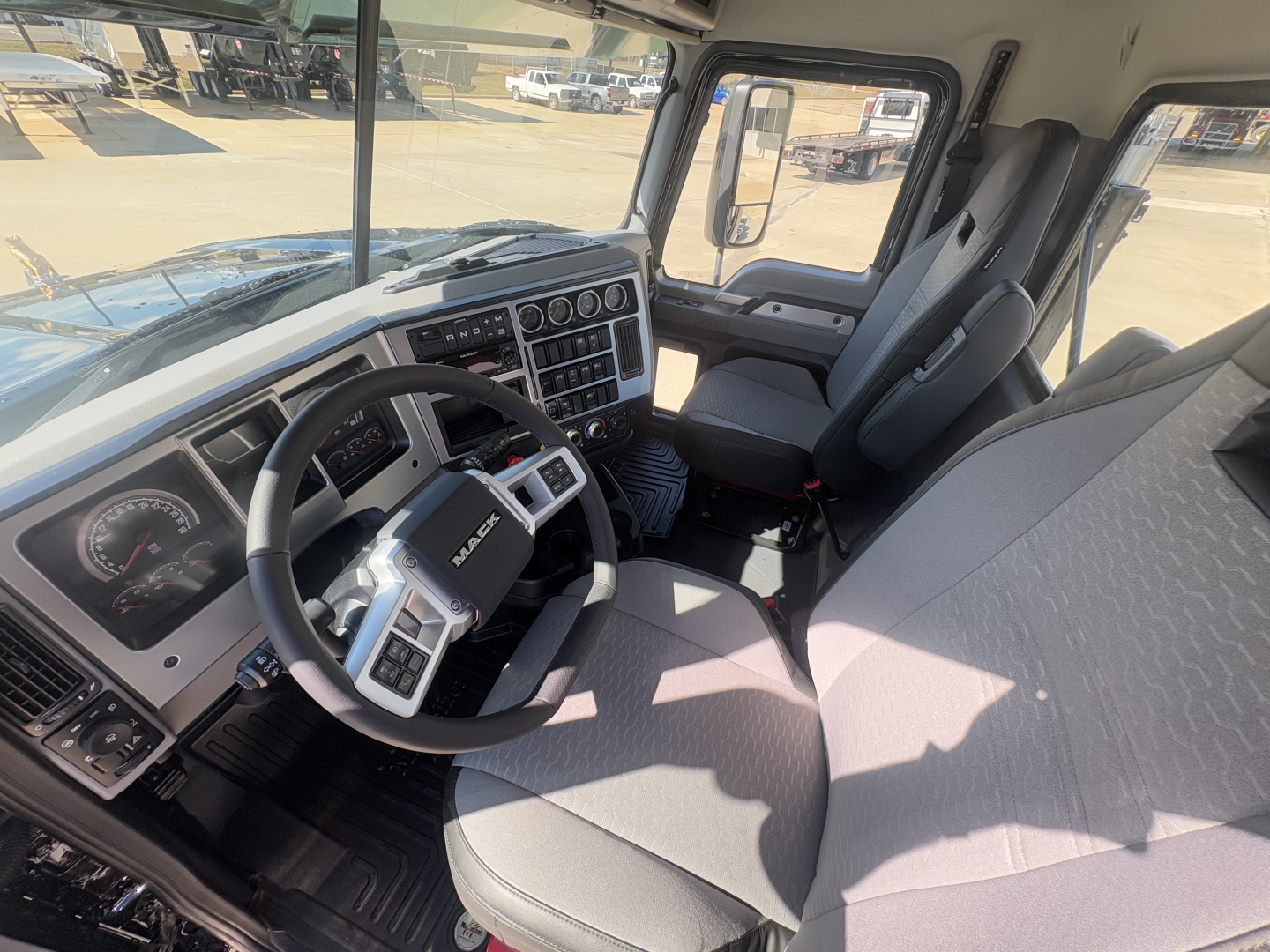 Cab interior of a 2026 Mack PI64T truck showing steering wheel, dashboard with gauges, driver seat, and front passenger seat.