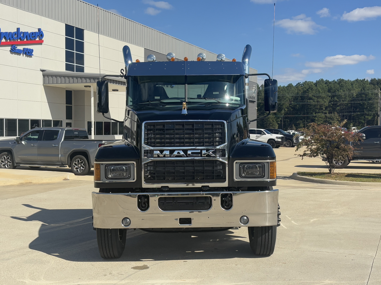 Mack PI64T conventional daycab truck front view showing grille with MACK letters and chrome bumper, headlights, and side mirrors.