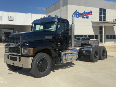 Mack PI64T conventional daycab truck showing front grille, chrome bumper, dual exhaust stacks, and large fuel tanks.