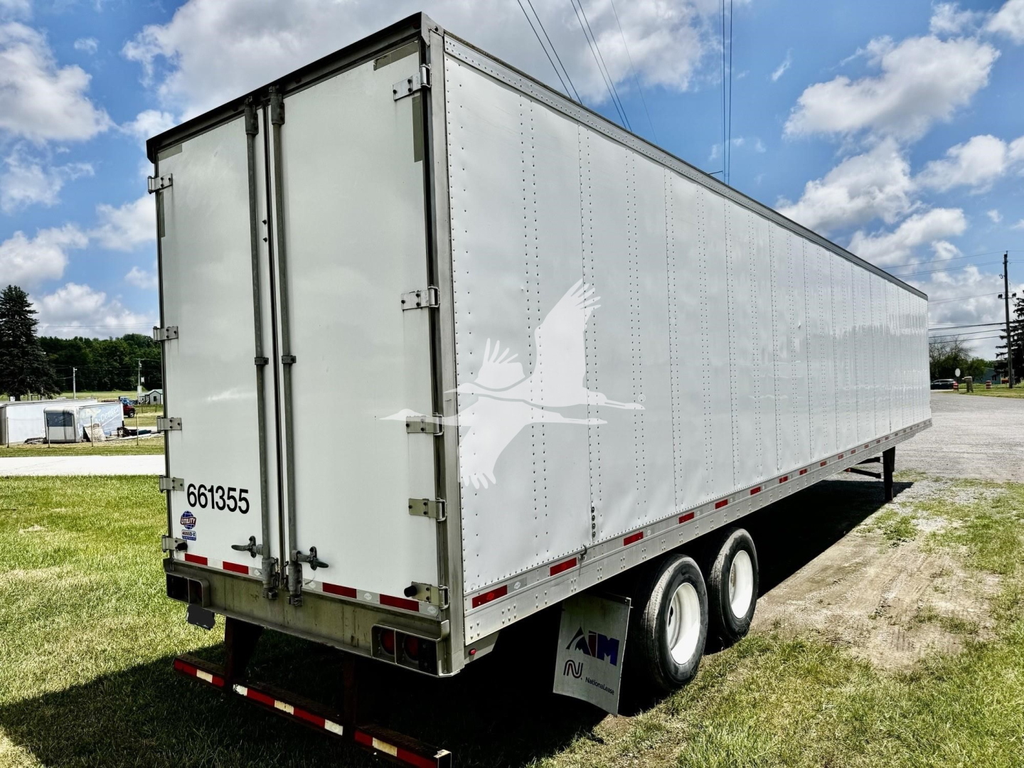 Trailer showing side and rear doors of a 2016 utility dry van with white exterior and triple-axle wheels.