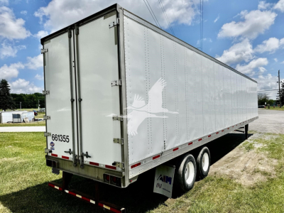 Trailer showing side and rear doors of a 2016 utility dry van with white exterior and triple-axle wheels.