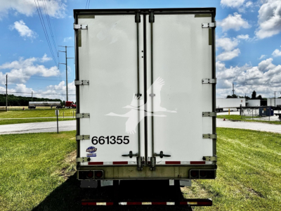 Rear view of a white utility dry van trailer showing two rear doors with vertical hinges, identification number 661355, reflectors, and a trailer chassis. License plate area and bumper visible.