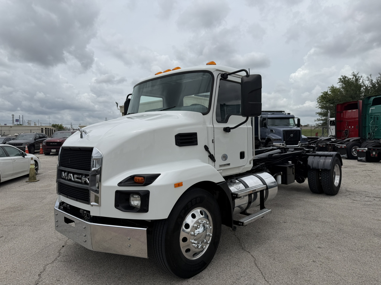 Mack MD6 hooklift truck in a lot showing front-left view with white cab and chrome bumper.
