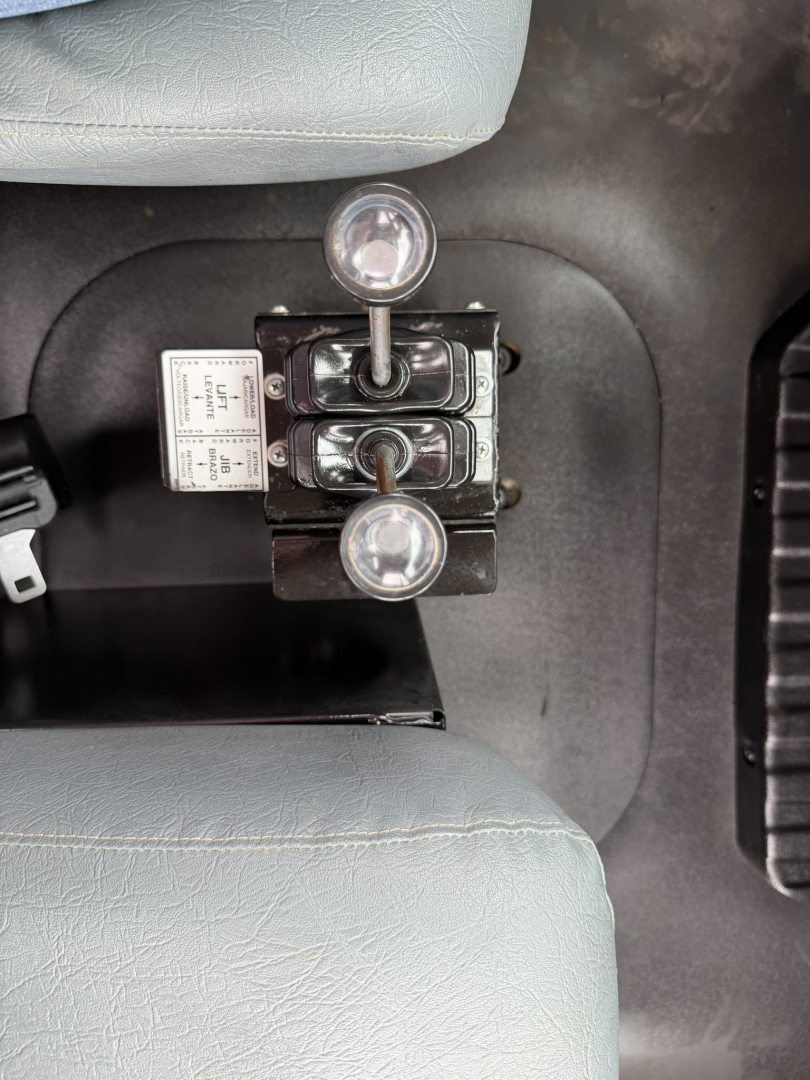 Mack MD6 cab interior showing hydraulic control levers and two round indicators between seats.