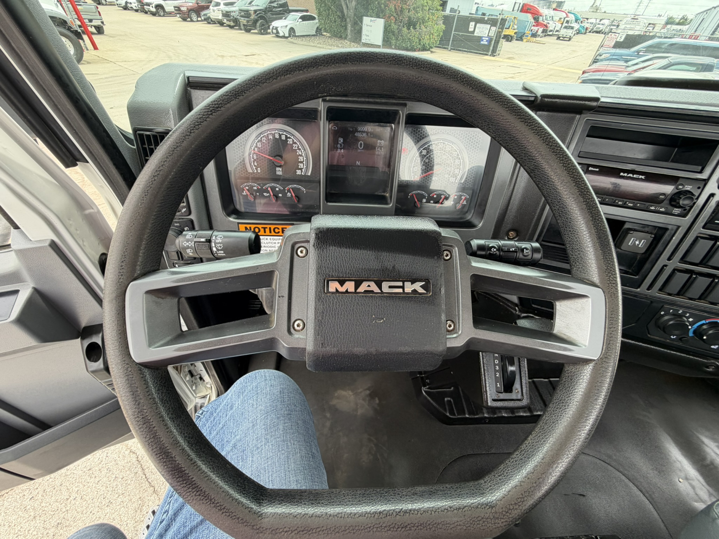 Mack MD6 truck steering wheel and instrument cluster seen from driver seat with dashboard controls.