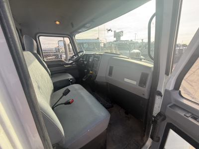 Truck cab interior of a Mack MD6 showing front bench seat, steering wheel, dashboard, and door panel.