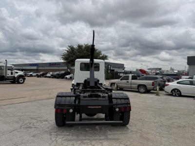 Rear view of a Mack MD6 hooklift truck chassis with fifth wheel and crane/backhoe? No, it's the cabless rear section showing a vertical exhaust stack and mounting frame. Visible text includes no legible labels from distance.