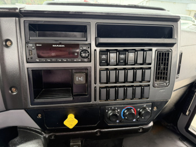 Mack MD6 dash showing radio, switches, climate controls, and storage pocket with yellow key tag.